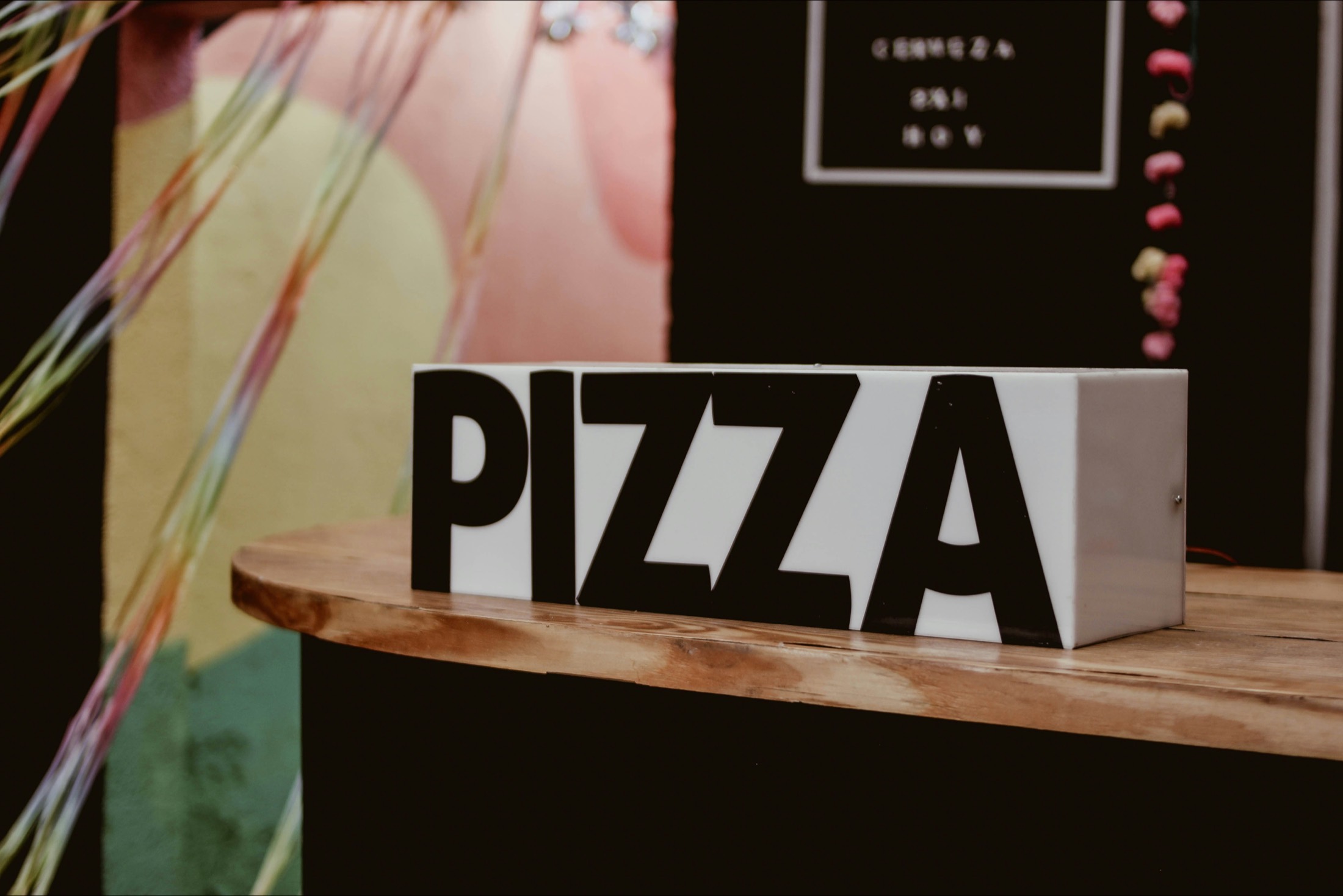 A black-and-white PIZZA light-box sign on a wooden counter